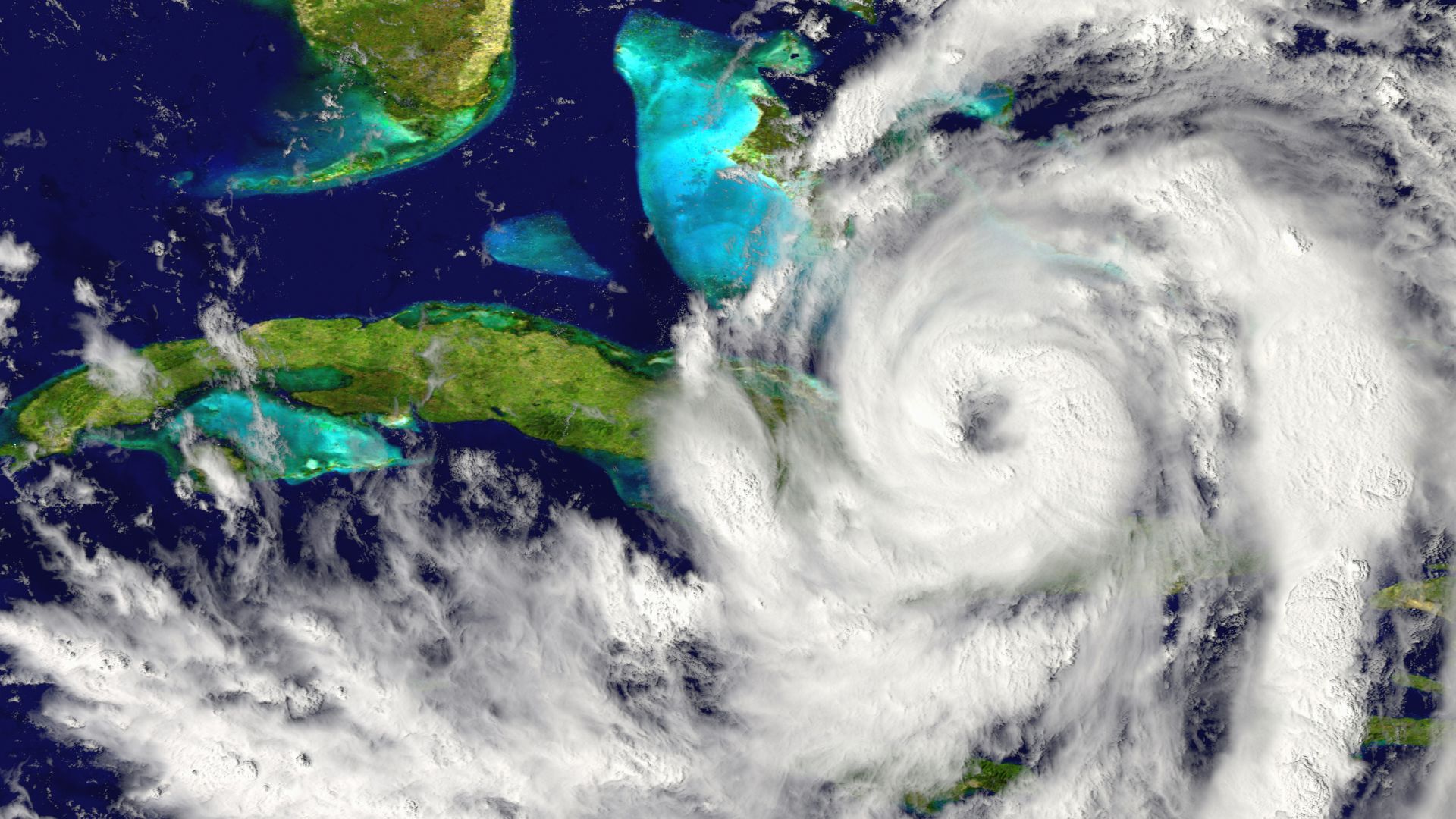 Imagem de satélite de um grande furacão girando sobre o Caribe com cobertura de nuvens densas visível.