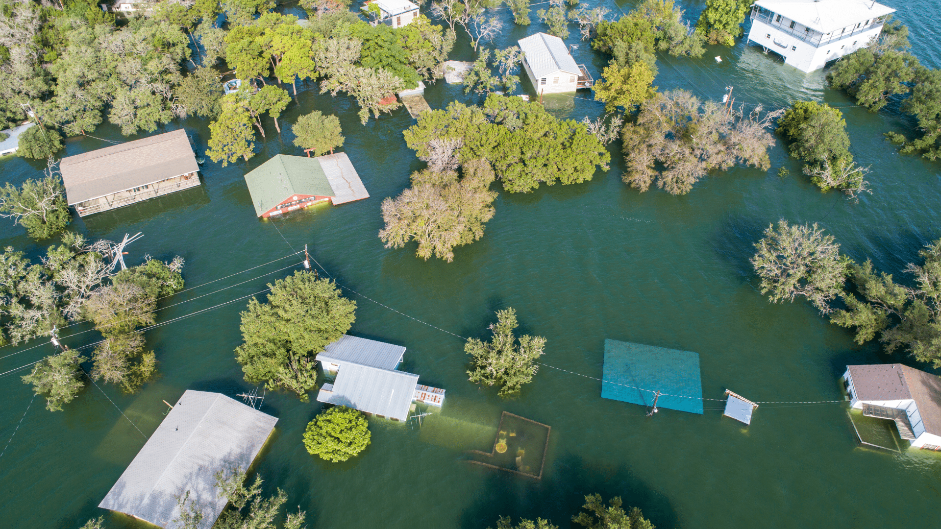 Visão aérea de uma área residencial alagada com casas e árvores parcialmente submersas em água após o furacão Ian.